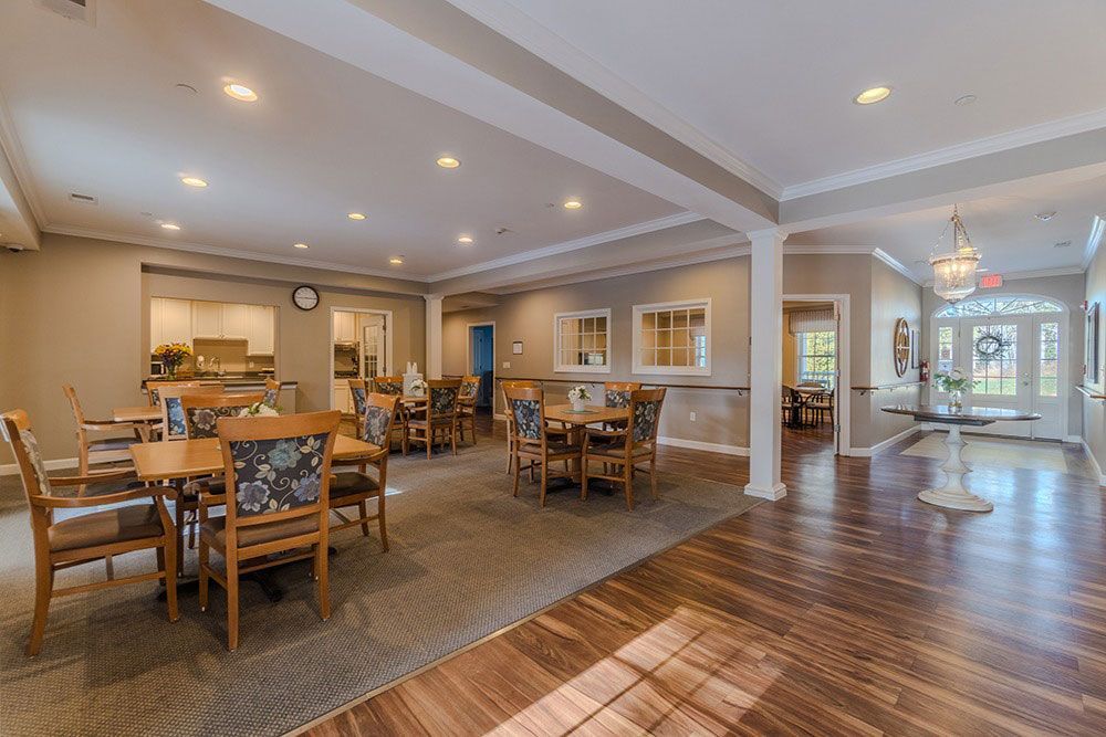 Spacious dining room with wooden tables, carpeted seating area, and polished hardwood floor under recessed lights