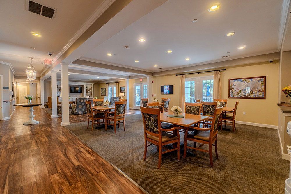 Spacious restaurant dining room with wooden tables, chairs, warm lighting, and polished wood flooring