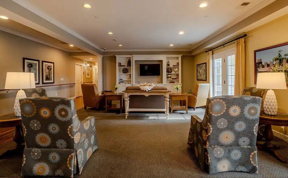 Cozy living room with two patterned armchairs, fireplace, sofa, and warm recessed lighting