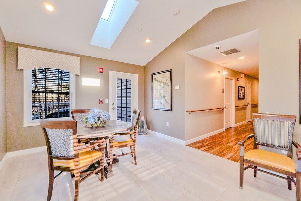 Bright dining area with round table, wicker chairs, and a hallway with wood flooring