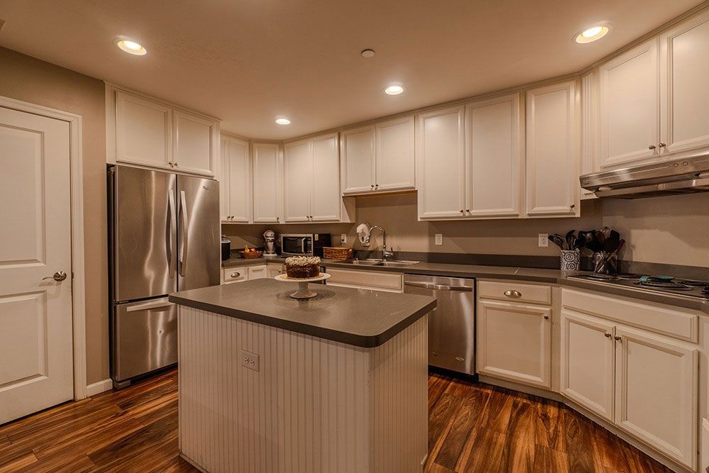 Bright modern kitchen with white cabinets, stainless steel appliances, and a central island with granite countertop