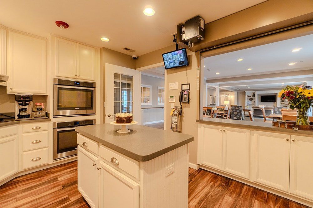 Bright modern kitchen with cream cabinets, wood floors, island, and a pass-through to a dining area