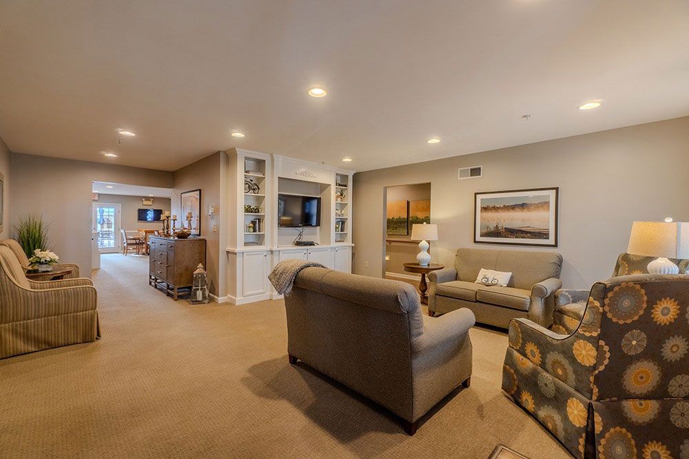 Spacious beige living room with sofas, armchair, lamps, and framed wall art under recessed lighting
