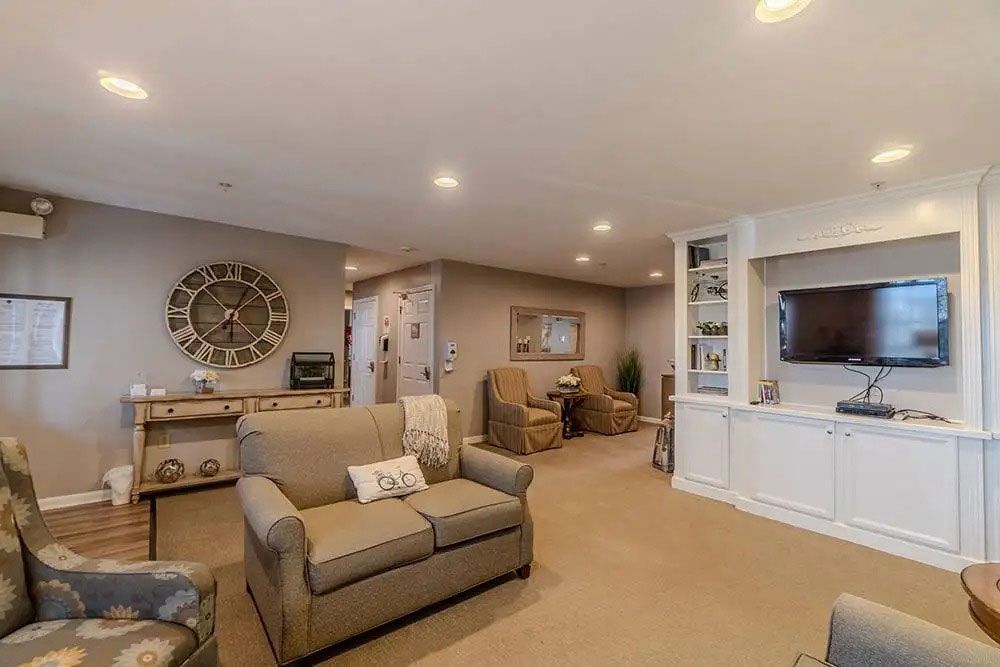 Bright living room with beige sectional, wall clock, and built-in TV cabinet in an open-plan home