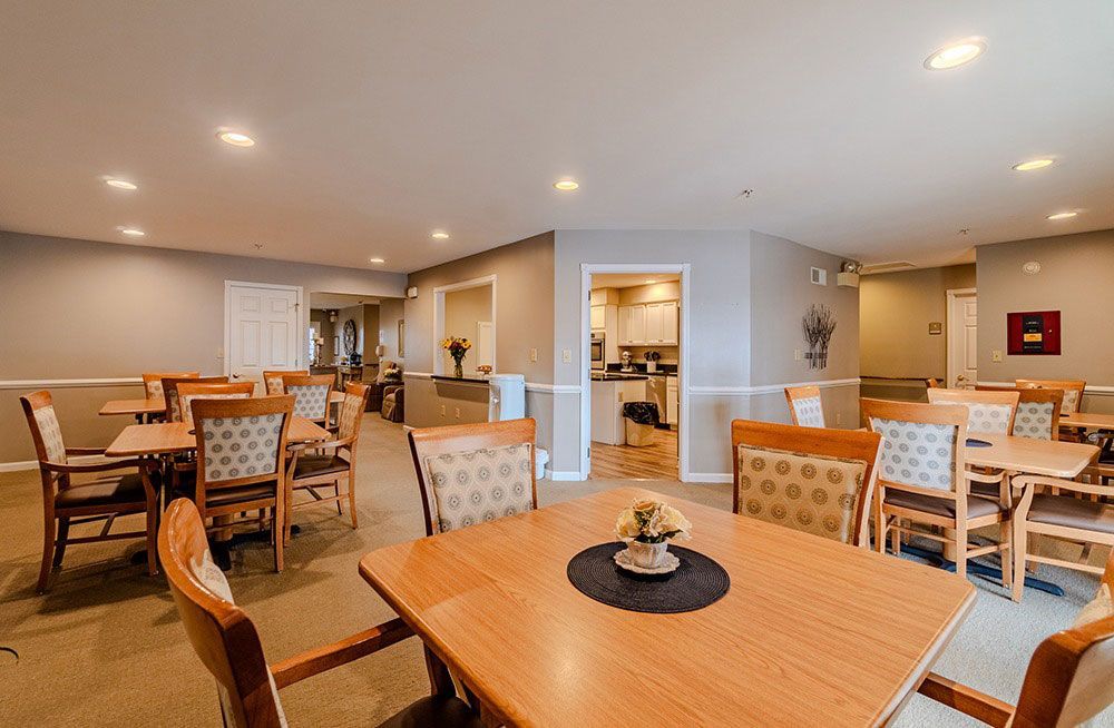 Spacious dining room with wooden tables and chairs, beige walls, and warm recessed lighting