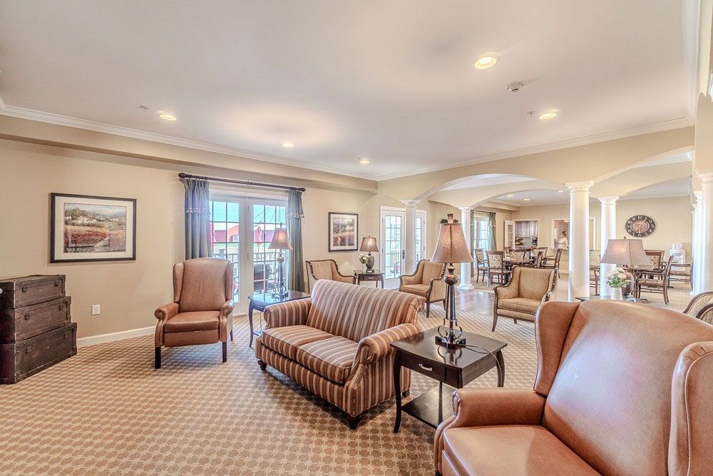 Spacious beige living room with striped sofa, leather chair, fireplace, and mirrored decor