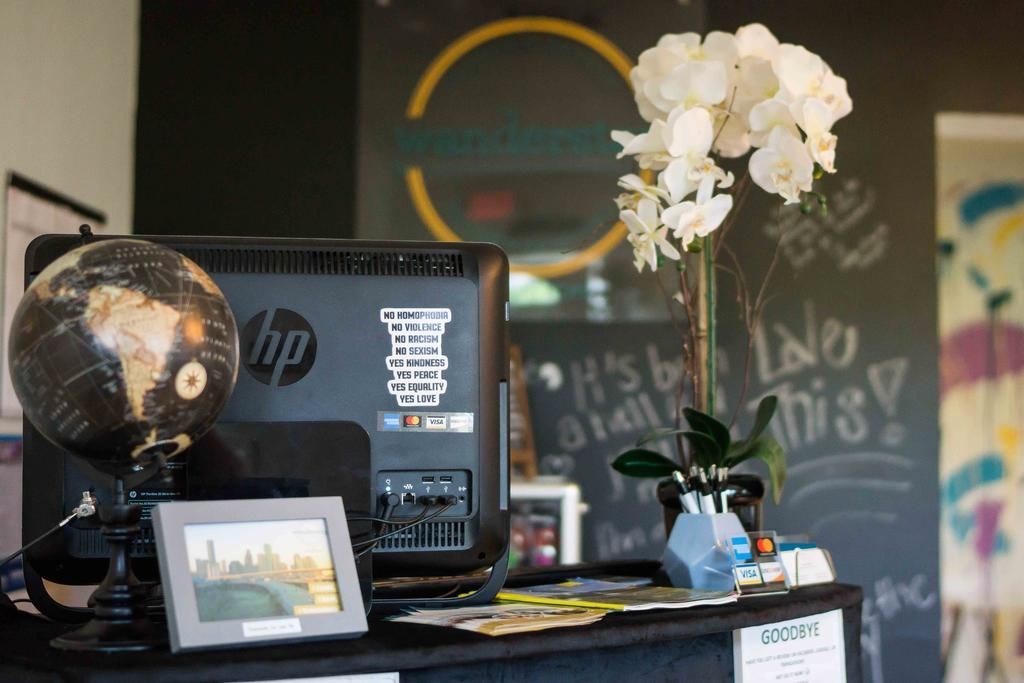 Reception desk with globe, computer, framed photo, and orchids in front of a dark wall with a logo.