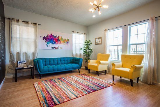 Waiting room with teal sofa, yellow armchairs, colorful rug, and skyline art.