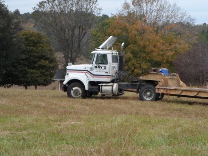 White truck with trailer in a grassy field;