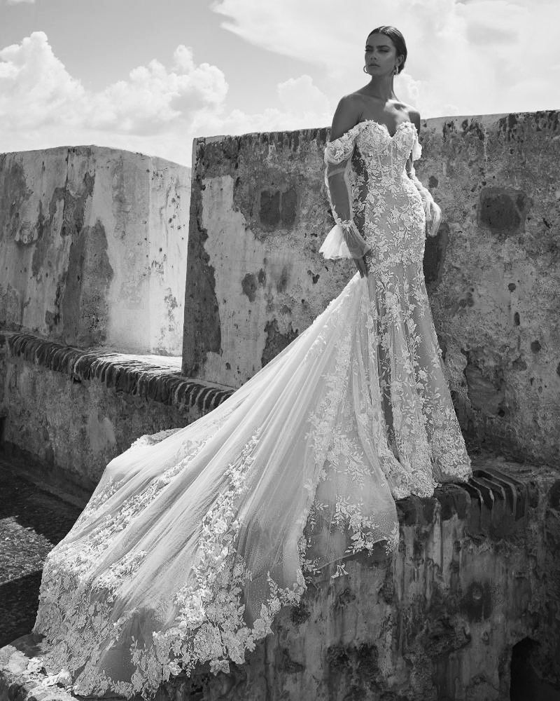 A woman in a wedding dress is standing on a wall.