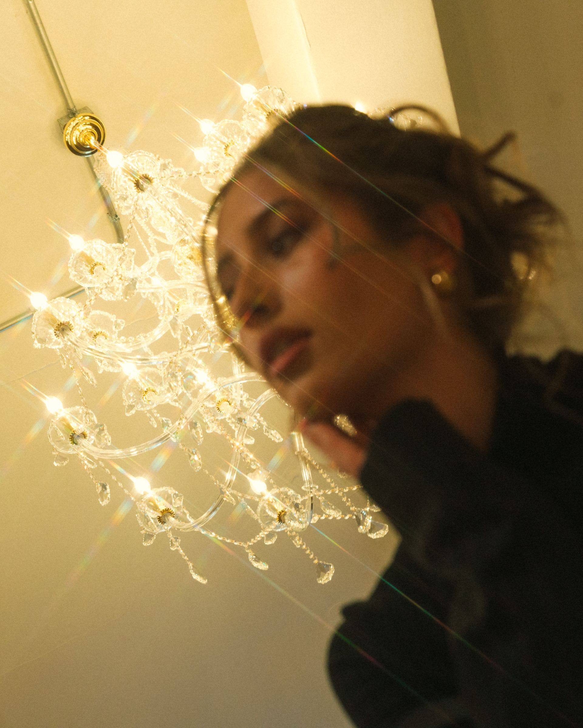 A woman is standing in front of a chandelier.