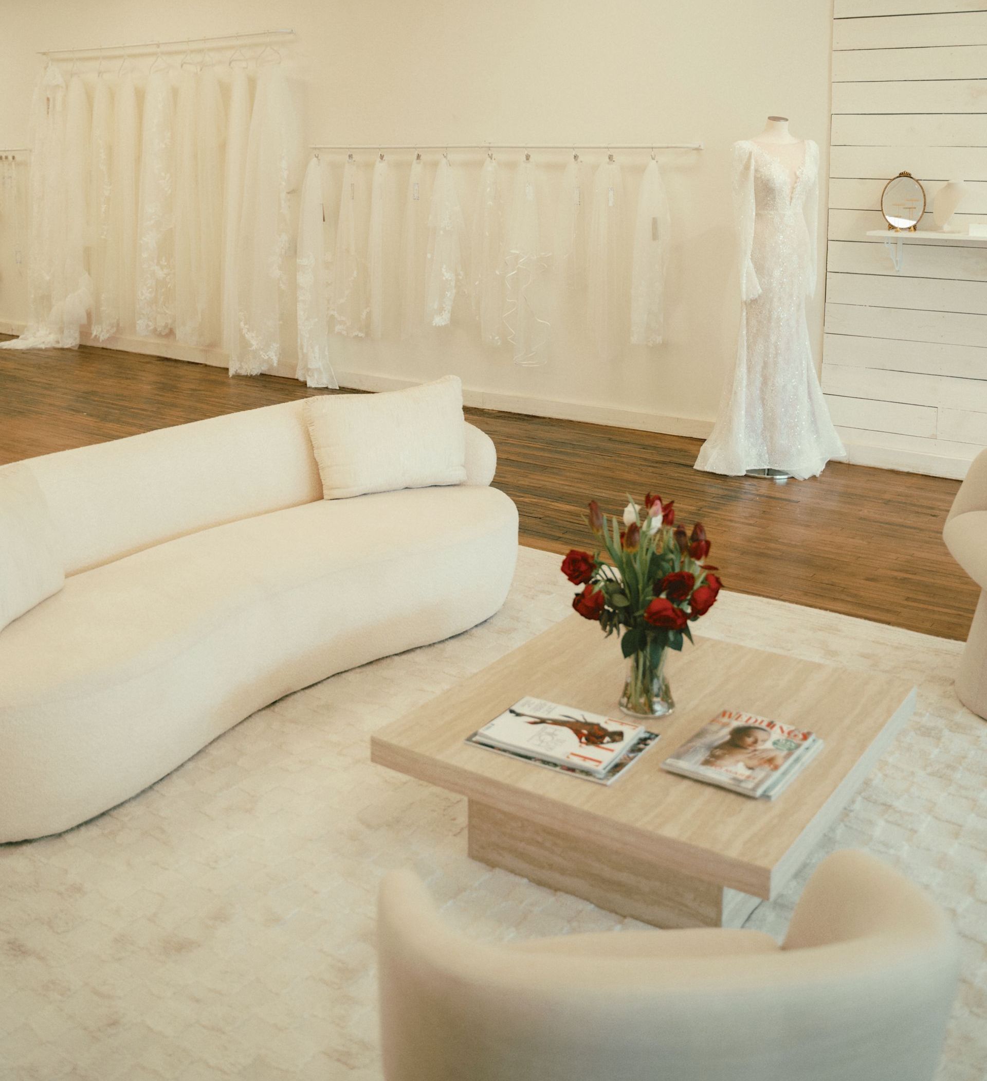 A room filled with lots of white dresses and a chandelier.
