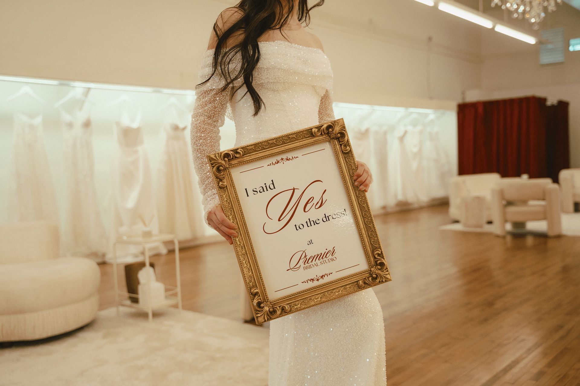 A woman in a wedding dress is holding a framed sign that says `` i said yes ''.