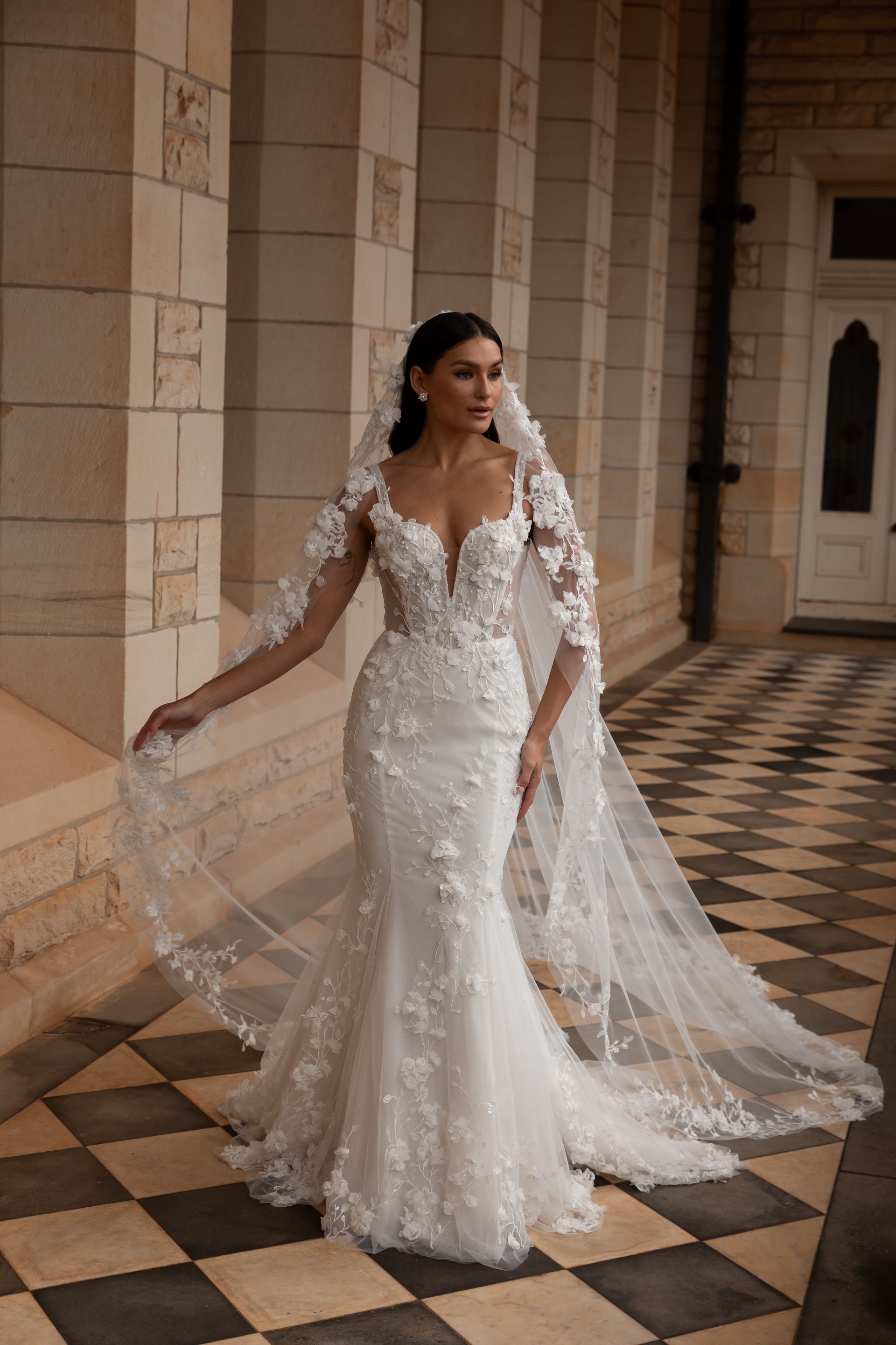 A woman in a wedding dress and veil is standing on a checkered floor.