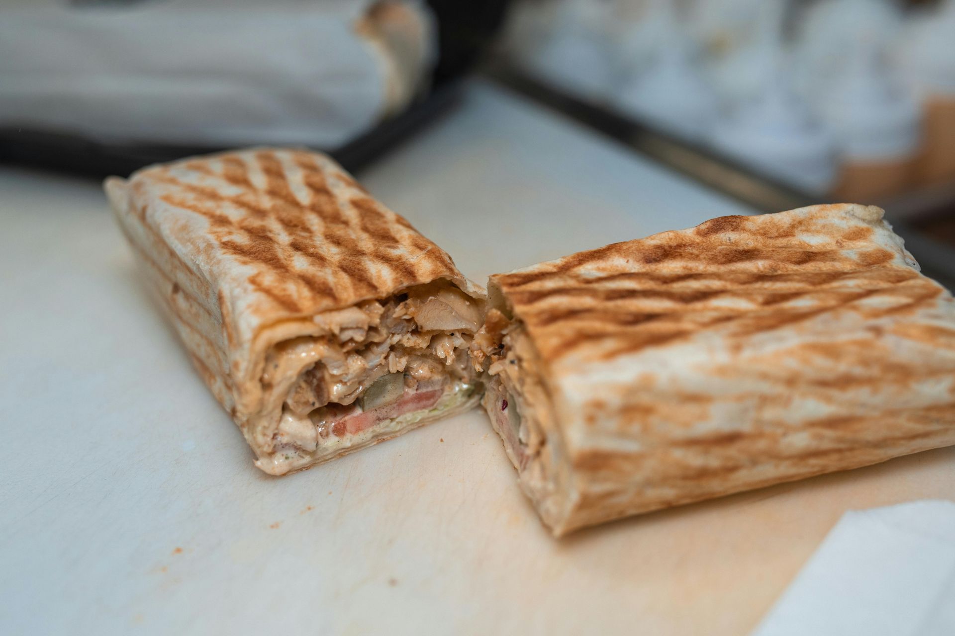 Grilled wrap sandwich cut in half, revealing filling.