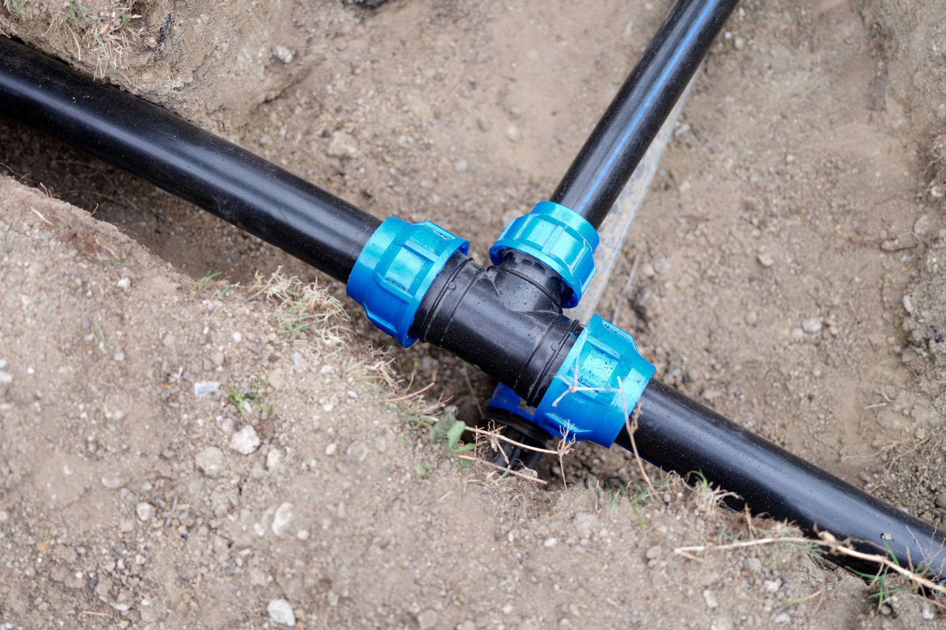 A close up of a hose connected to a pipe in the dirt.