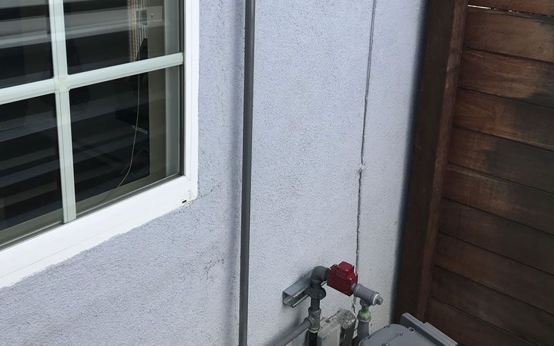 a white wall with a window and a red valve on it