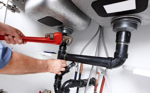 a plumber is fixing a sink pipe with a wrench .