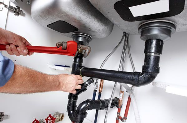 a plumber is fixing a sink pipe with a wrench .