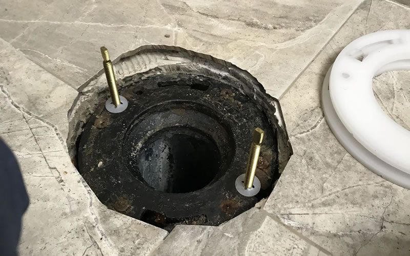 a hole in the floor with two screws in it