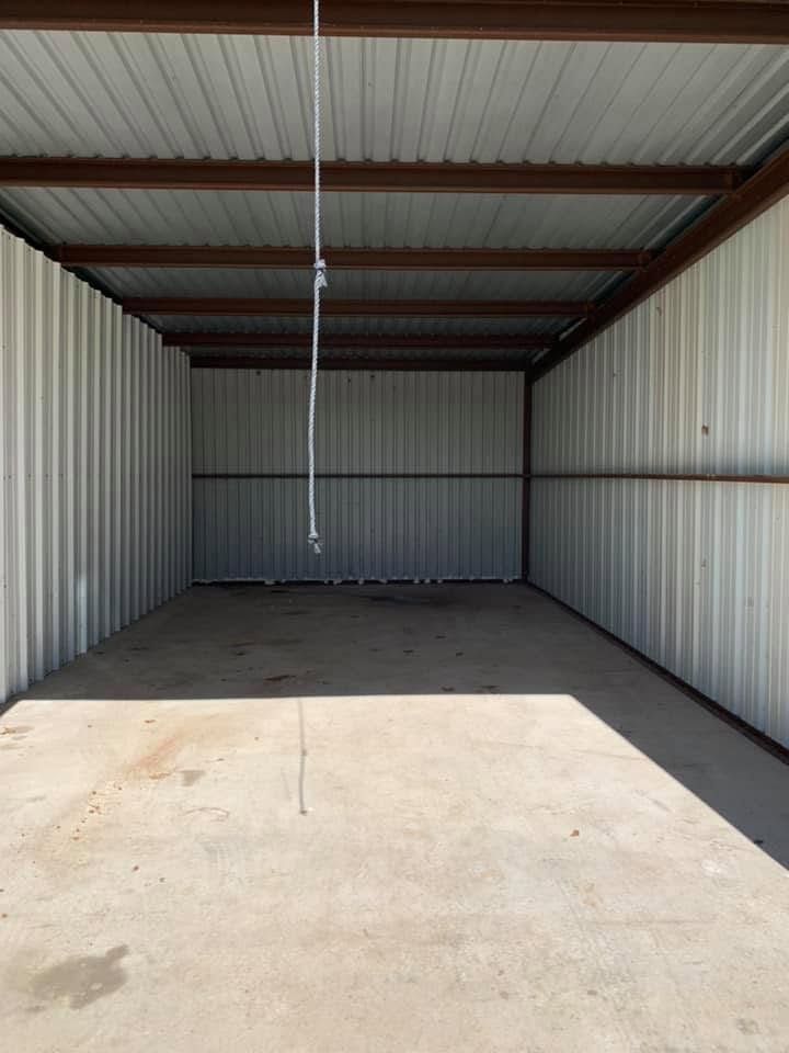 Empty metal storage container with a concrete floor and a hanging cord.
