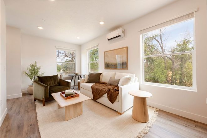 Modern living room with hardwood floors and an area rug, furnished, with multiple large windows