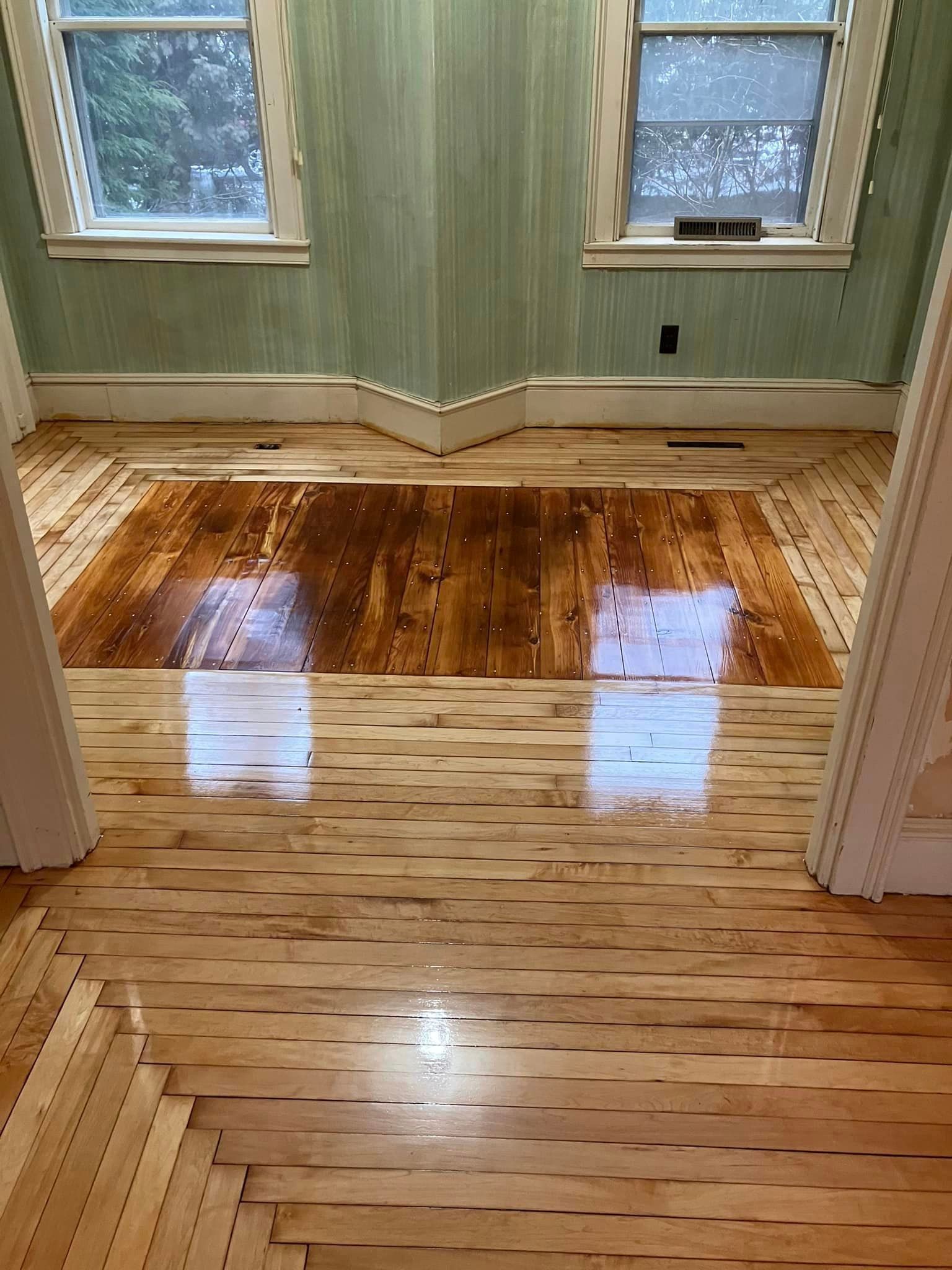 A room with a wooden floor and two windows.