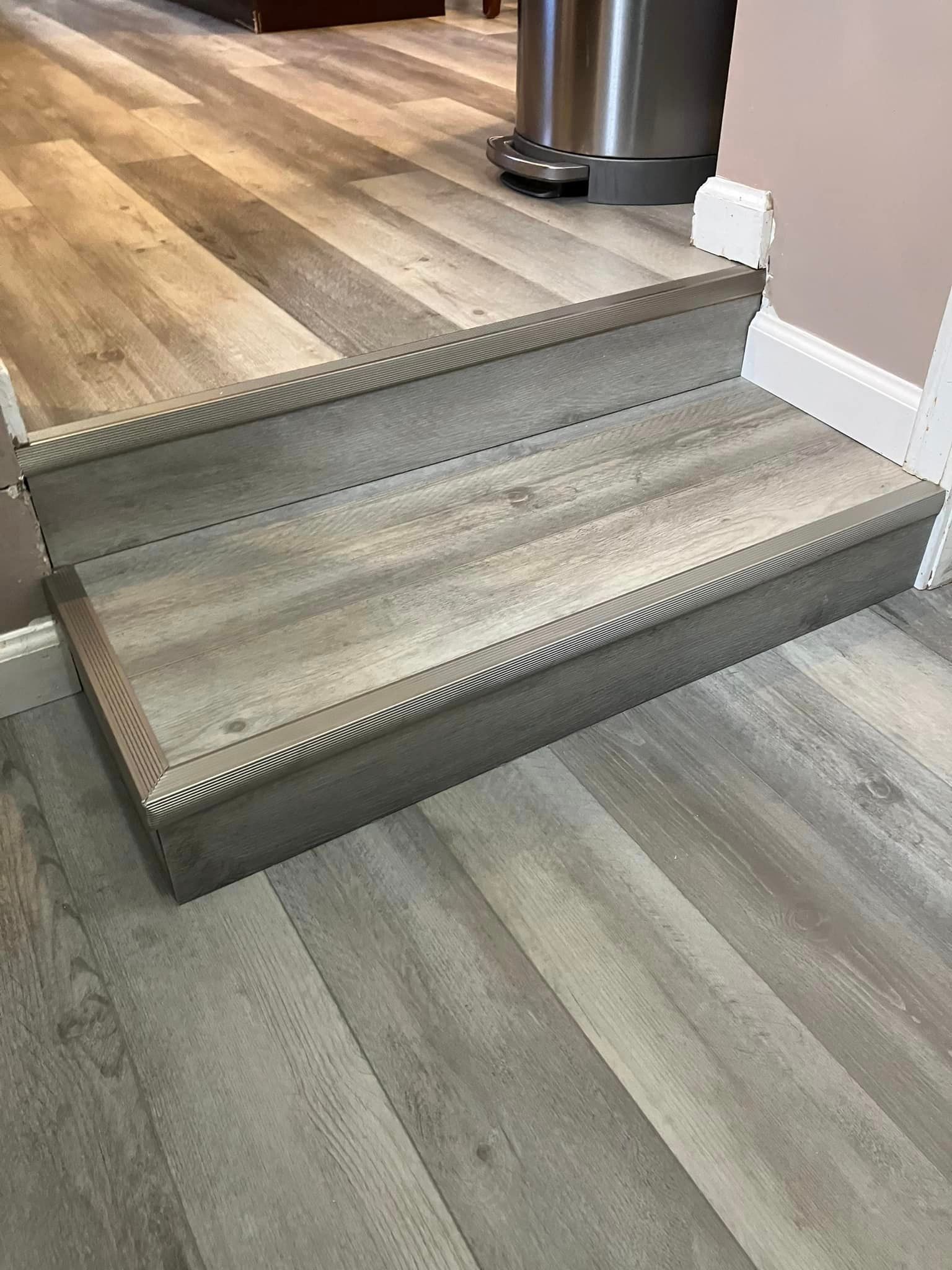 A set of stairs with a wooden floor and a trash can in the background.