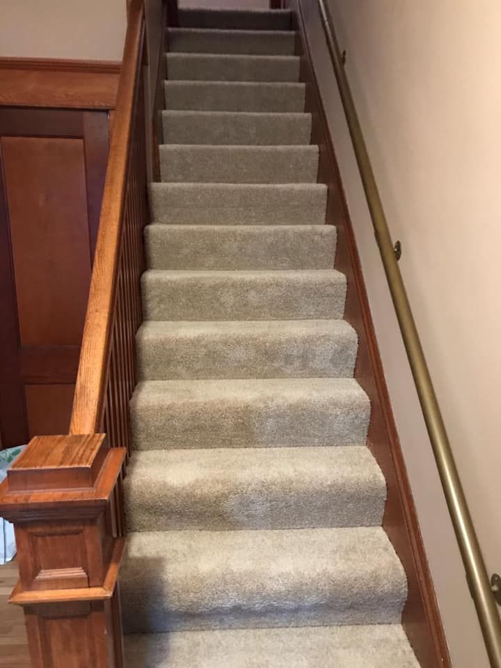 A set of stairs with a wooden railing and a carpeted staircase.