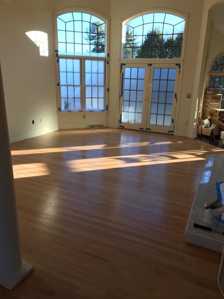 A room with a wooden floor and two windows.