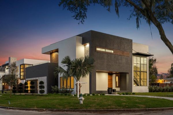 A modern house with a lot of windows is sitting on a lush green lawn.