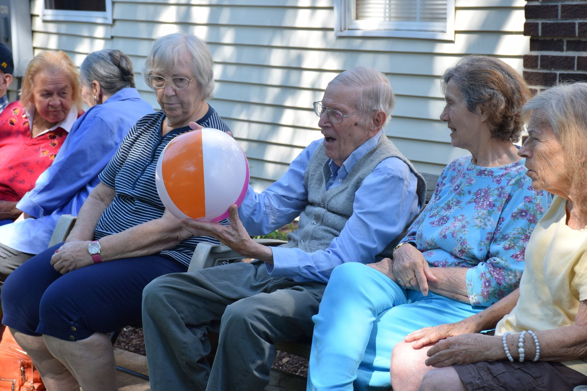 Aged memory care caregiver supporting seniors with engaging activities in a comfortable setting.