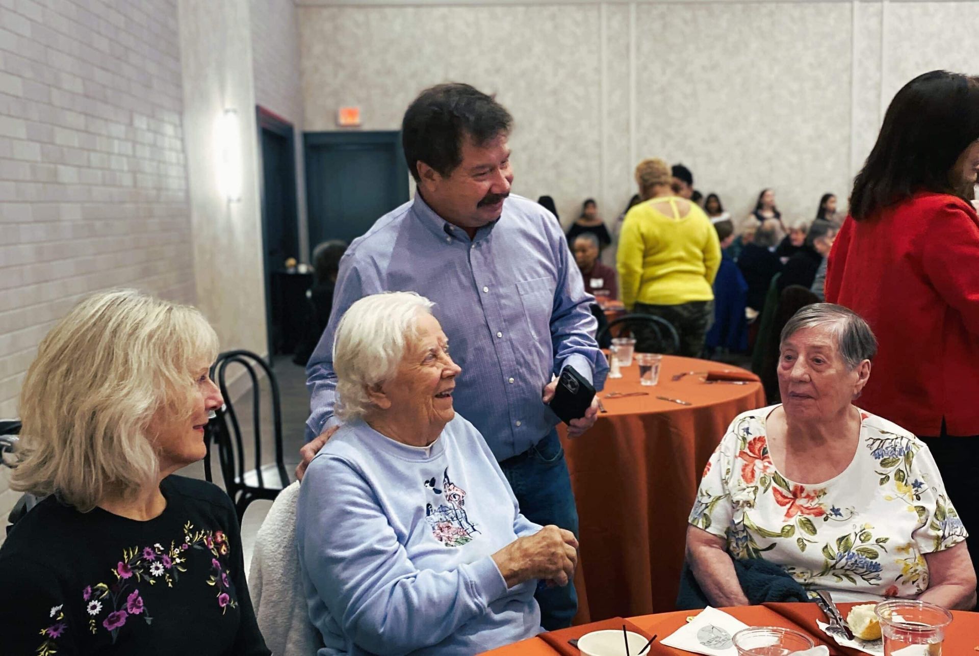 People talking at a banquet table in a bright community hall