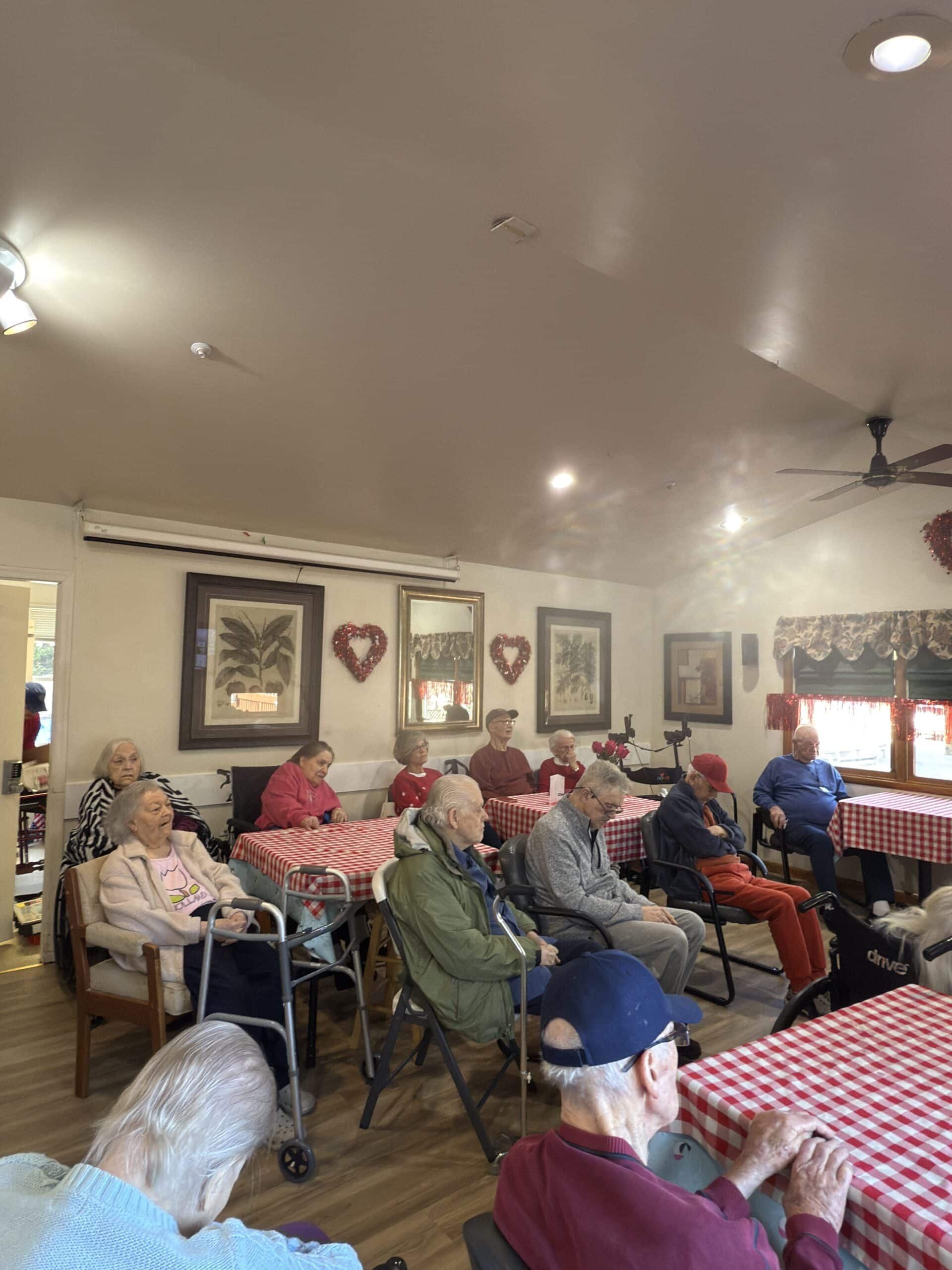 People seated at red-checkered tables in a bright dining room, with framed wall art and ceiling fans.