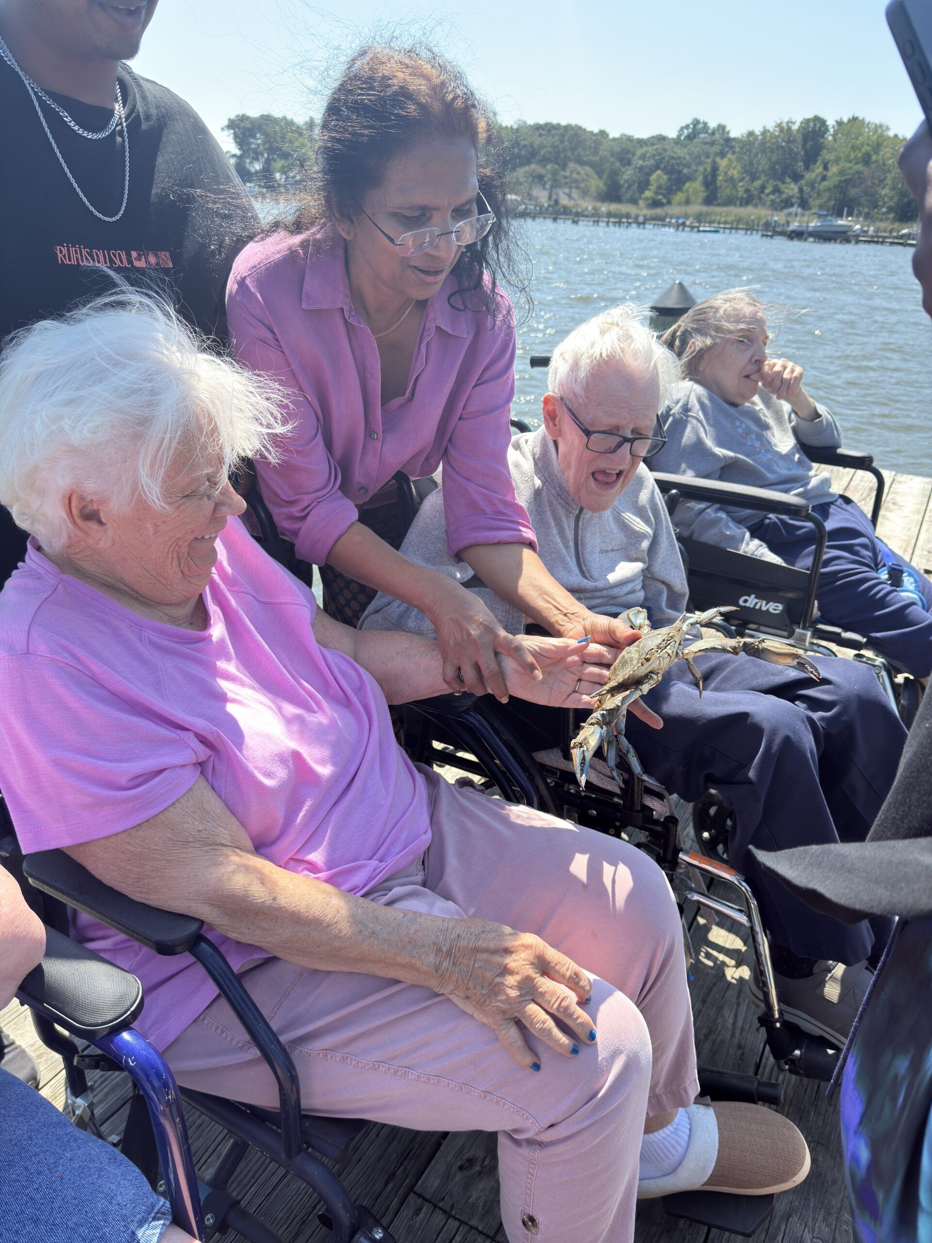 People seated on a boat holding a fish, with water and shoreline in the background