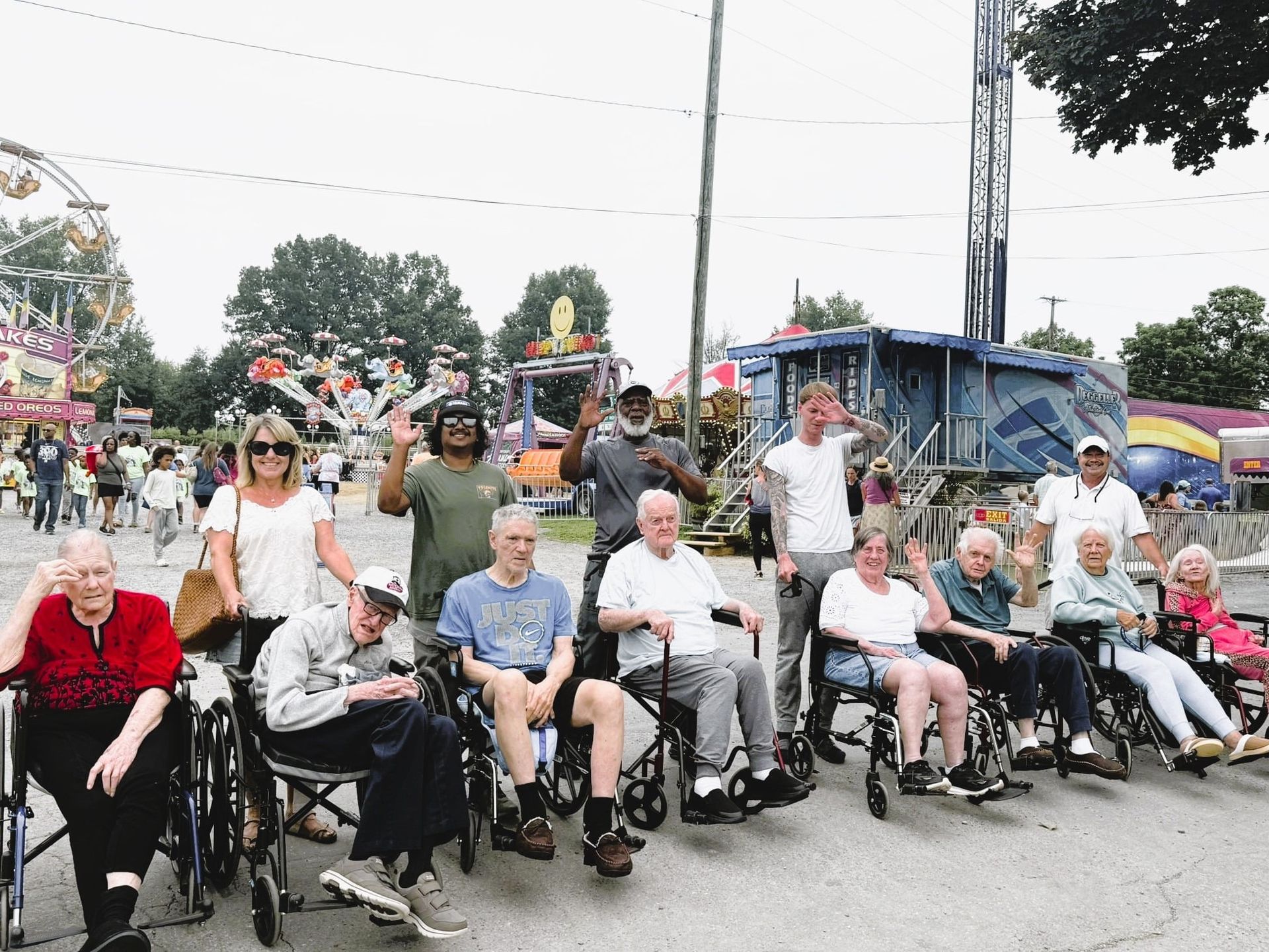 Group of people in wheelchairs and walkers posing outdoors at a community event