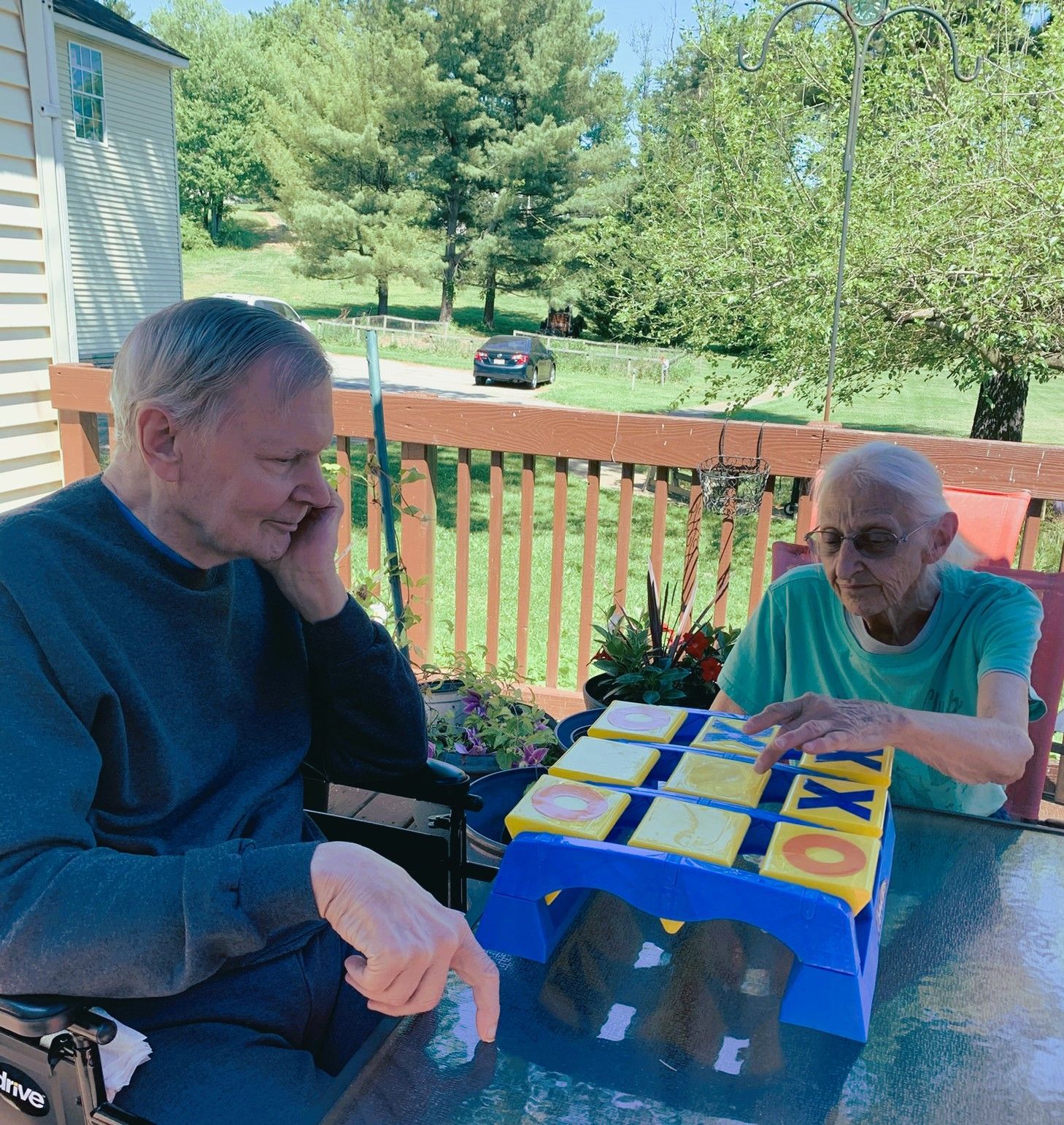 Two people playing a board game on a sunny porch with a blue and yellow game board