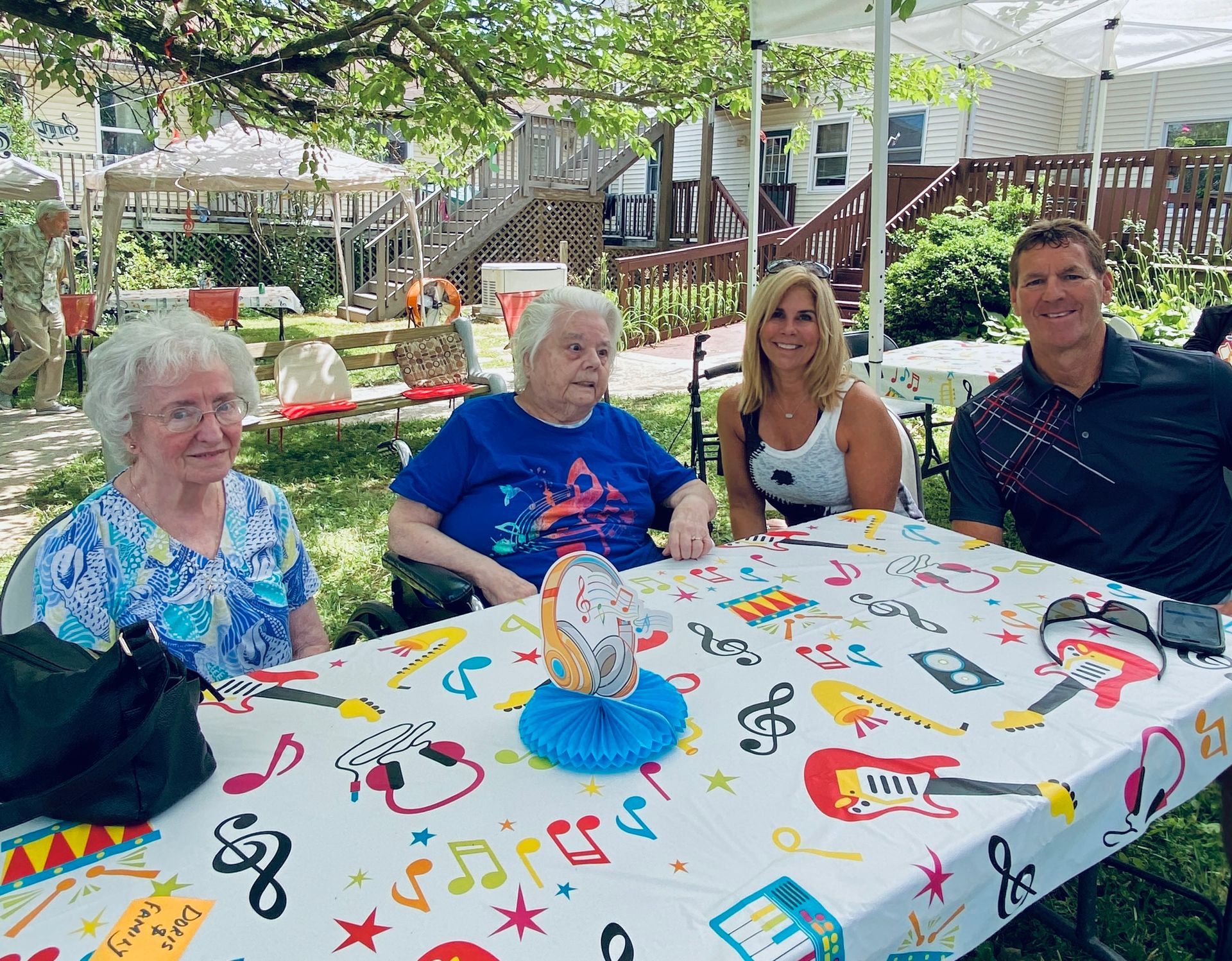 Four people sitting at a decorated outdoor birthday table in a garden backyard