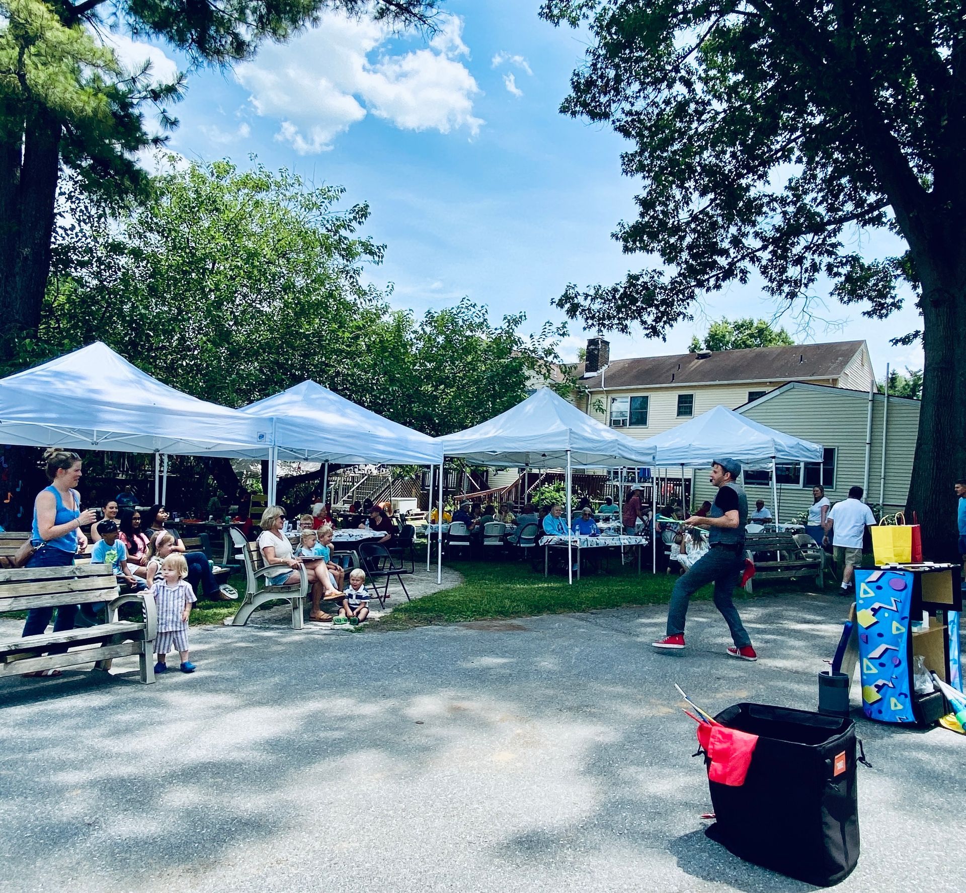 Outdoor community market under white tents with people browsing on a sunny day