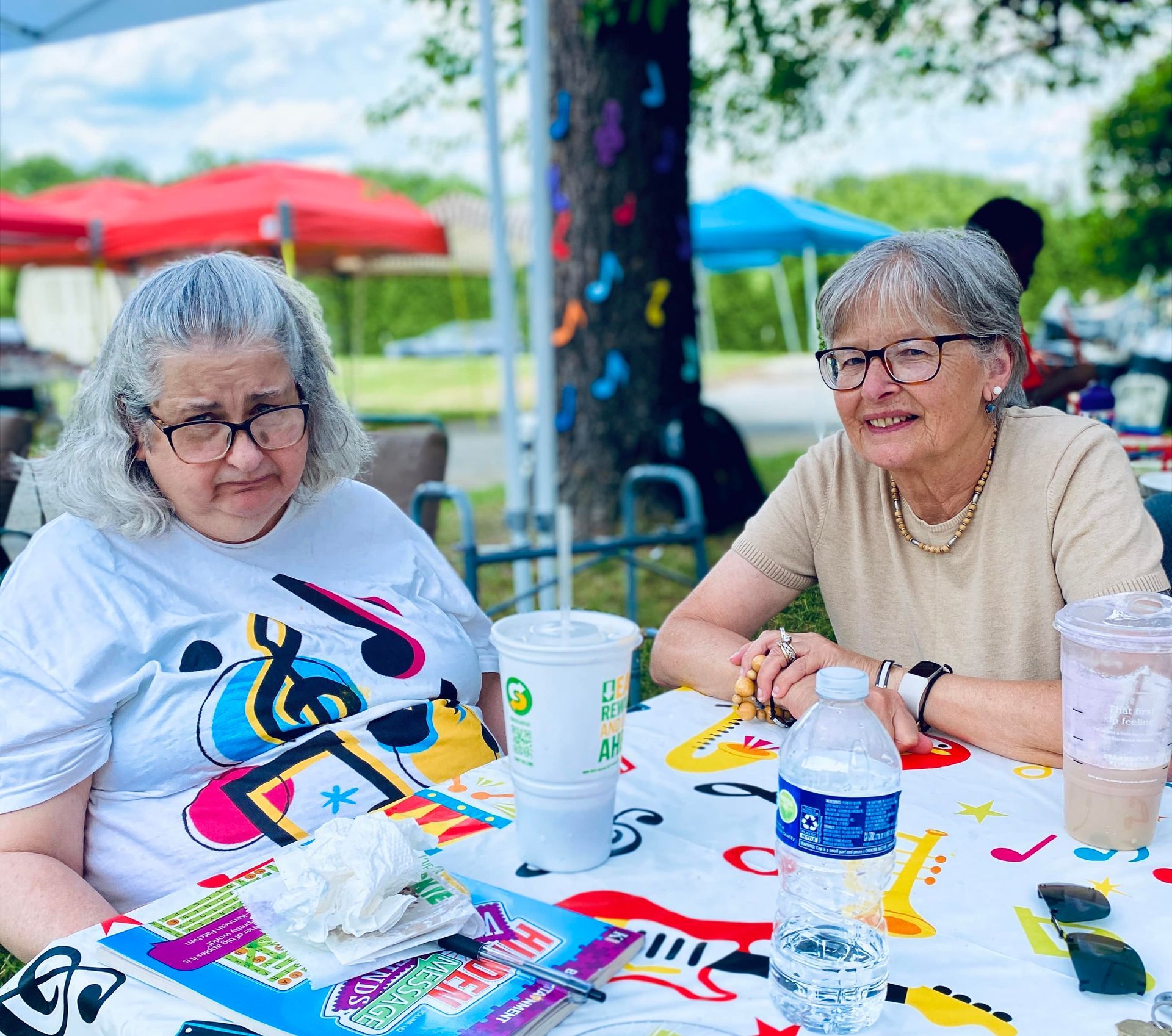 Two women sitting at a colorful outdoor picnic table, smiling and chatting