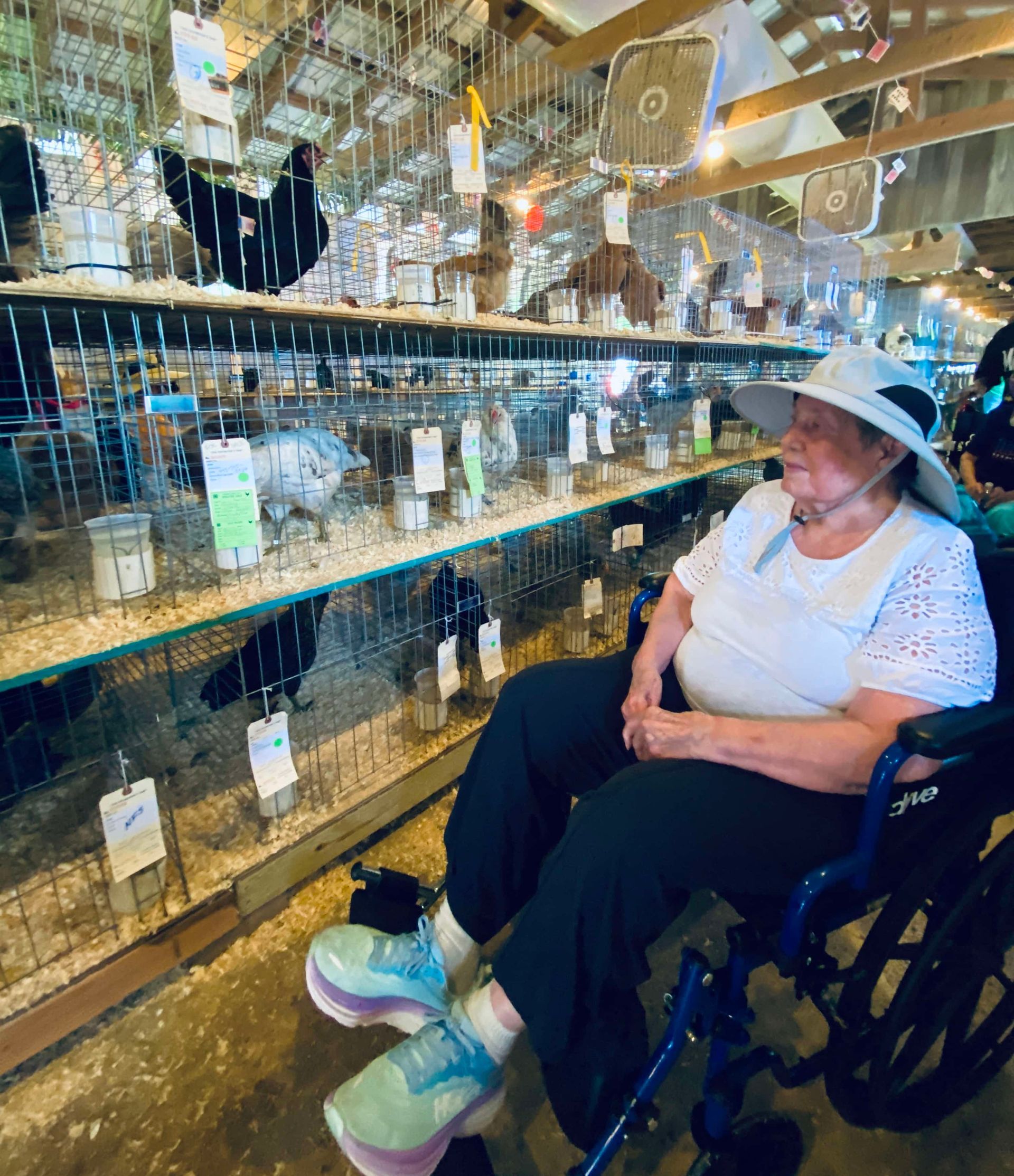 Person in a wheelchair smiling in a bright mirrored room with hanging decorations.