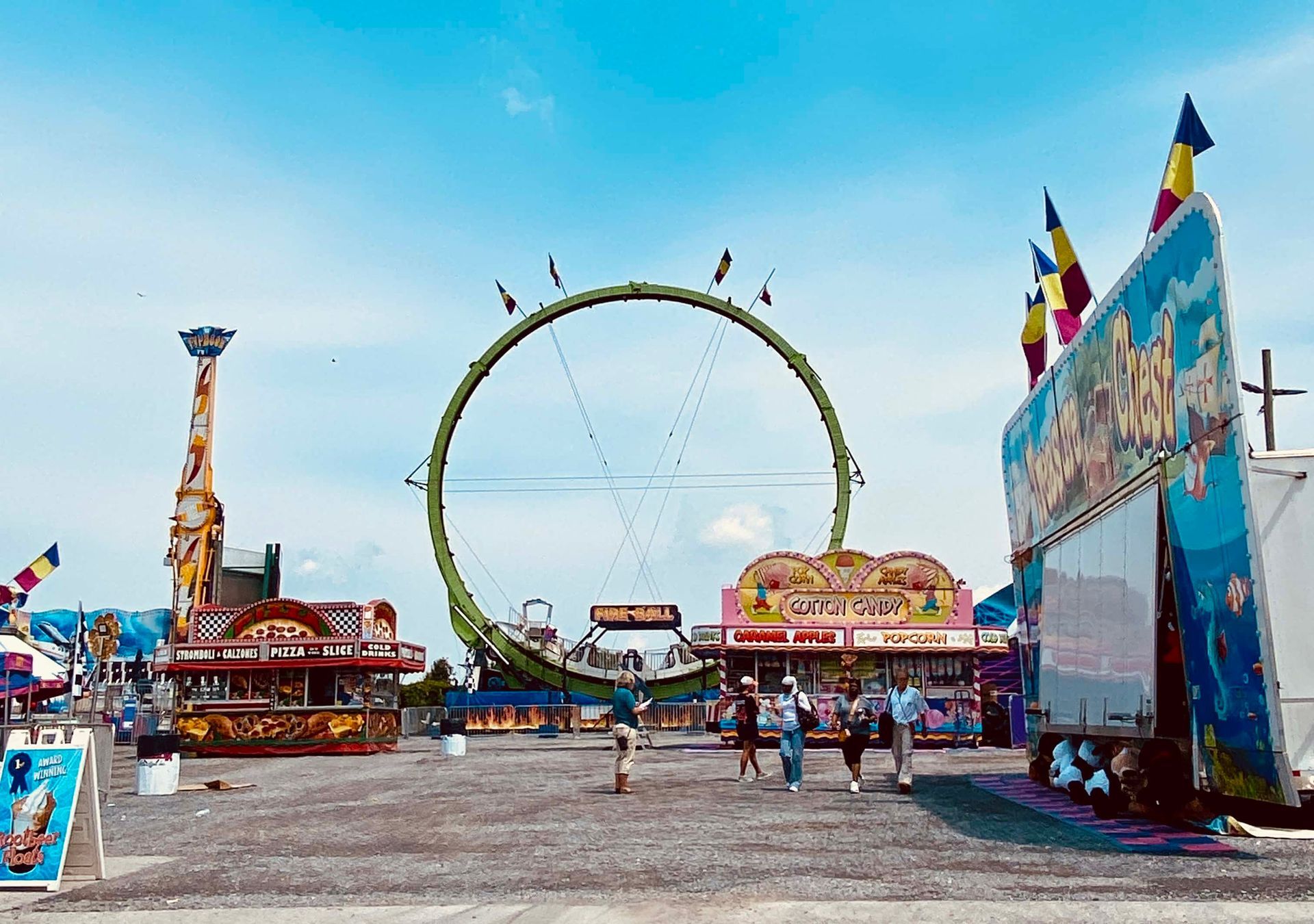 Amusement park with a large Ferris wheel, colorful rides, and people walking on a bright day