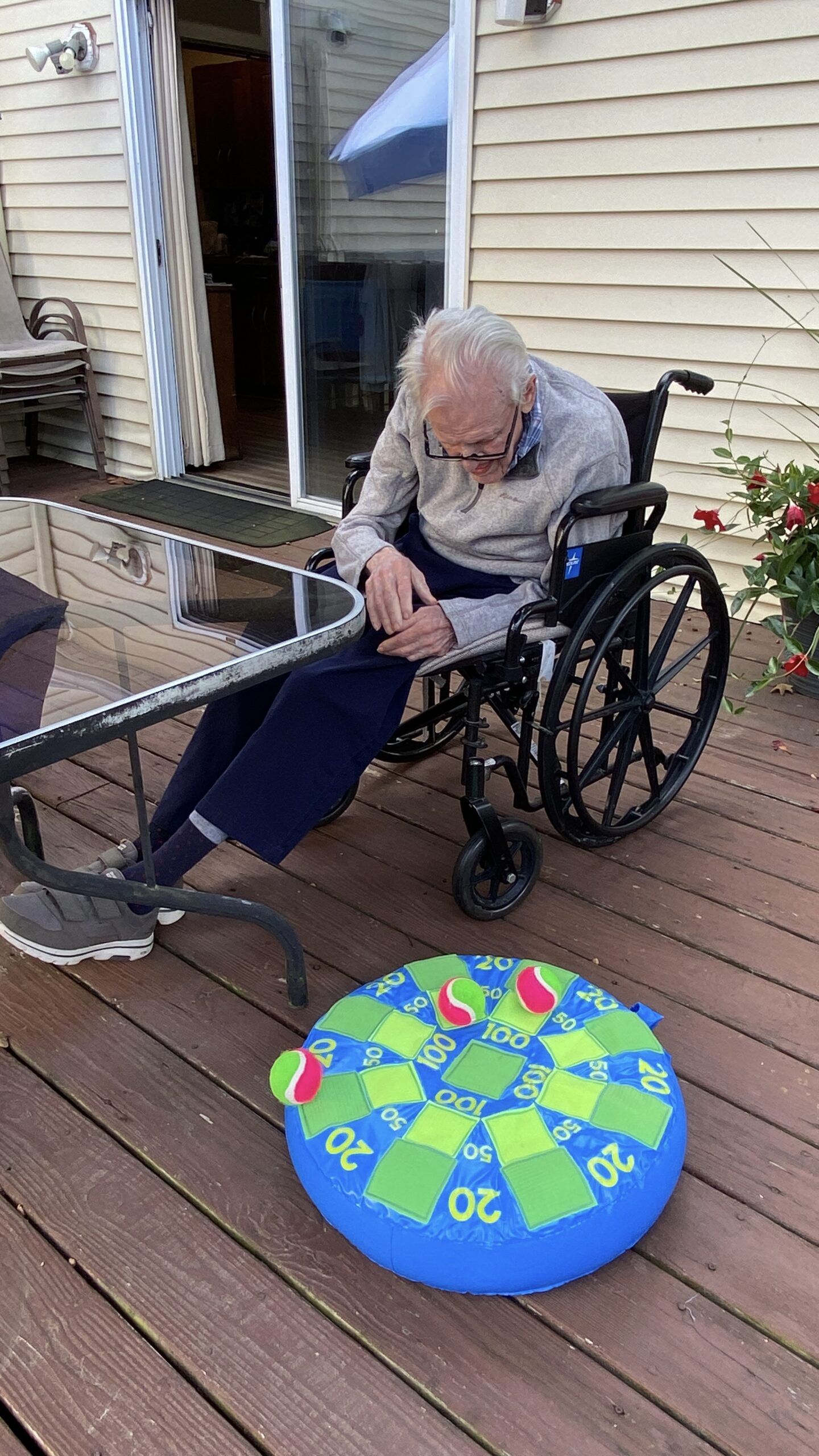 Person in a wheelchair on a wooden deck beside a colorful wheel game board.