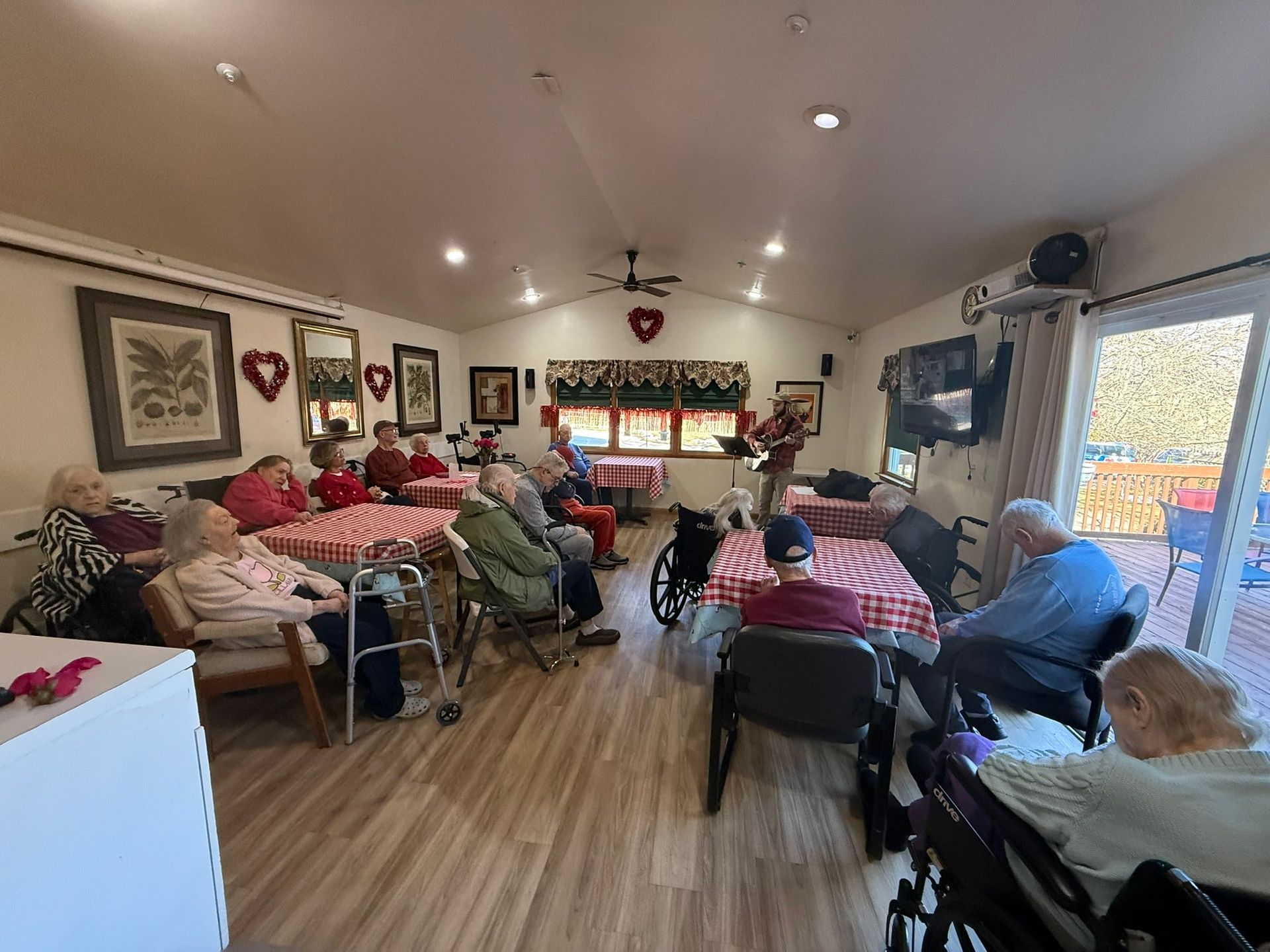 Cozy room with several people seated on beds and chairs, gathered in a decorated communal space.