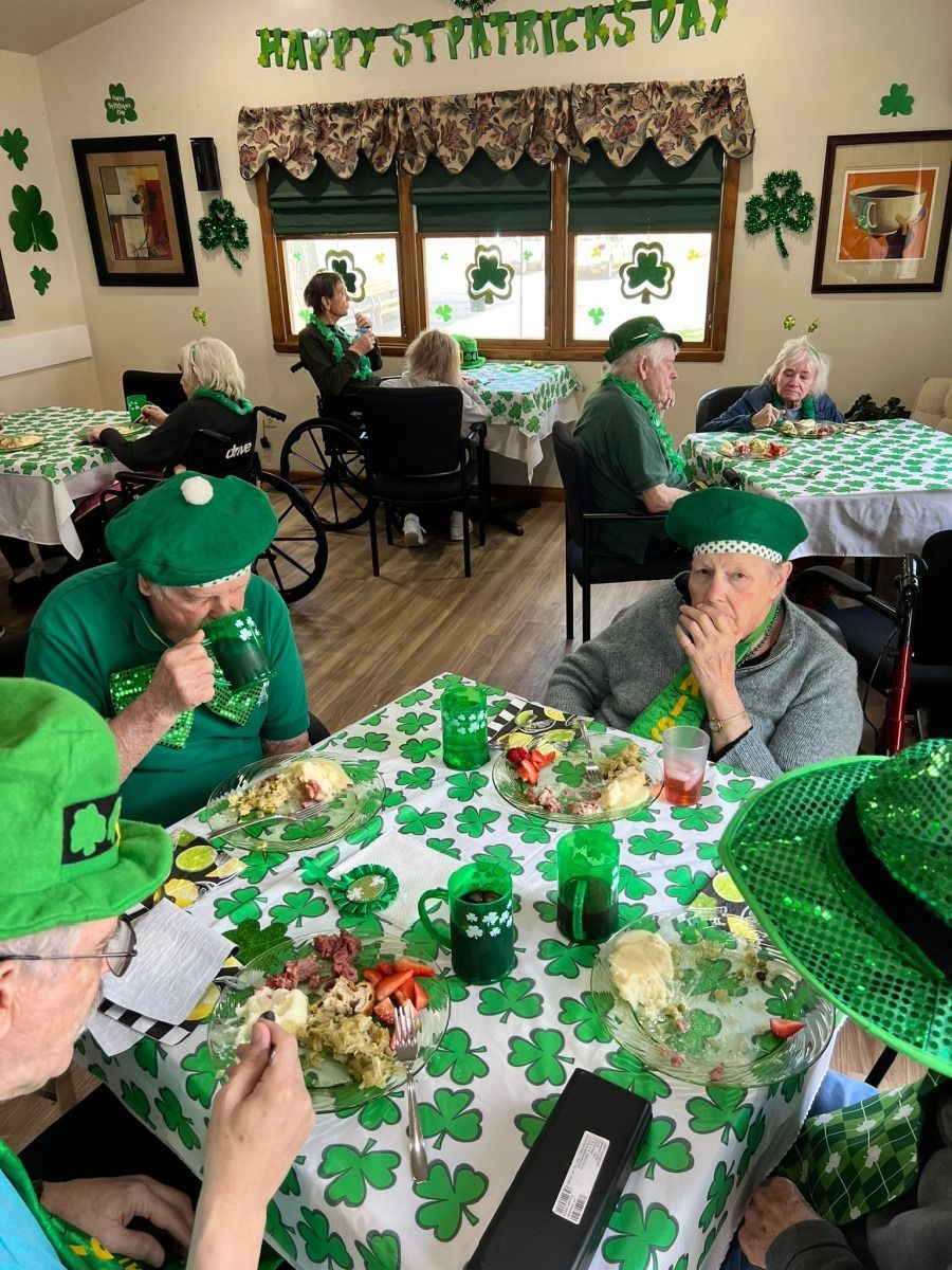 People in green hats eat at a St. Patrick’s Day decorated table in a home dining room.