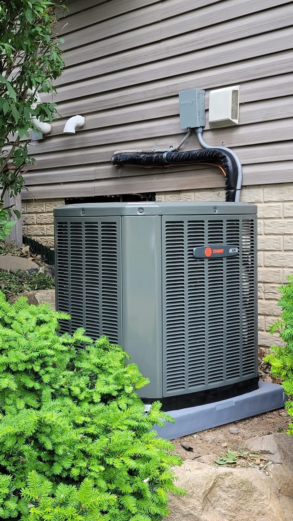 An air conditioner is installed on the side of a house.