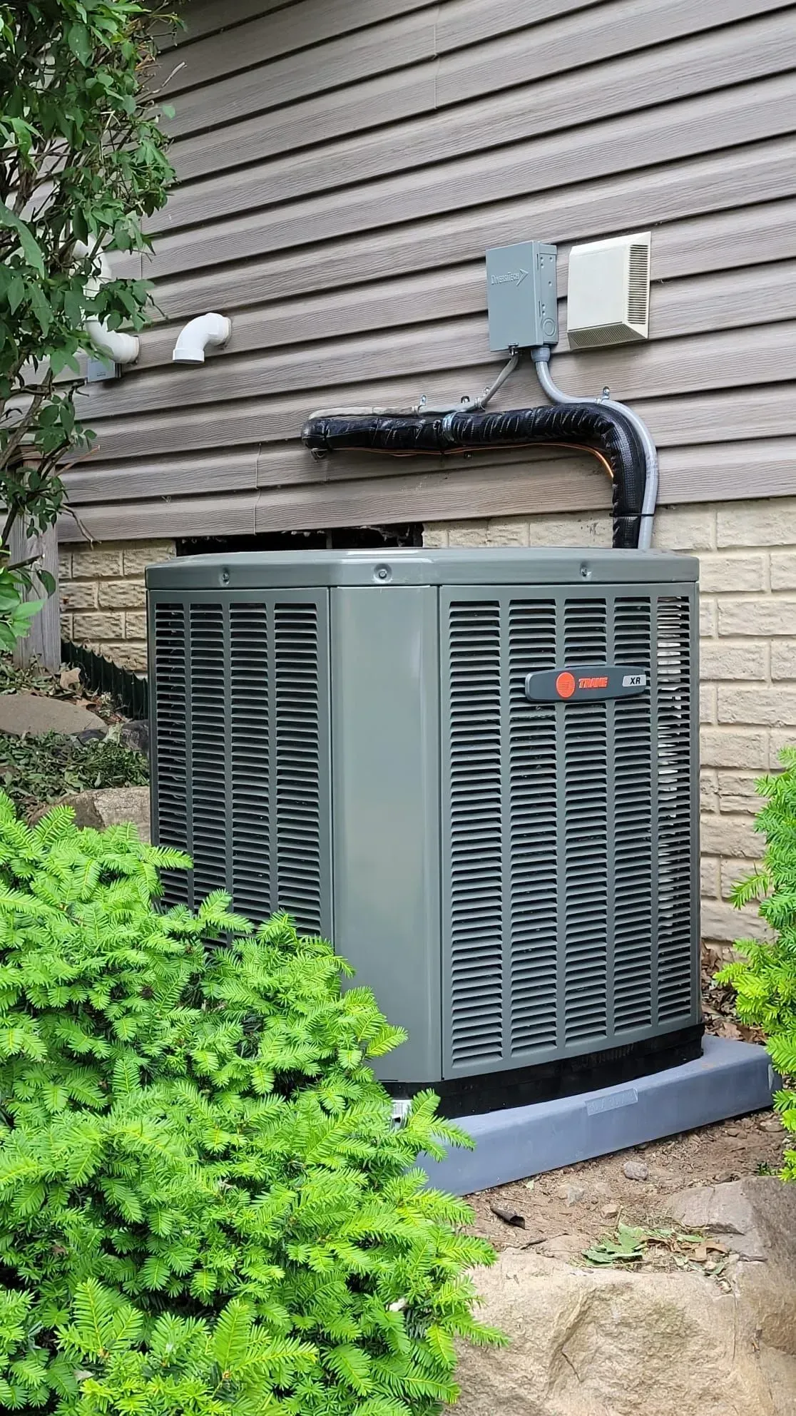 An air conditioner is installed on the side of a house.
