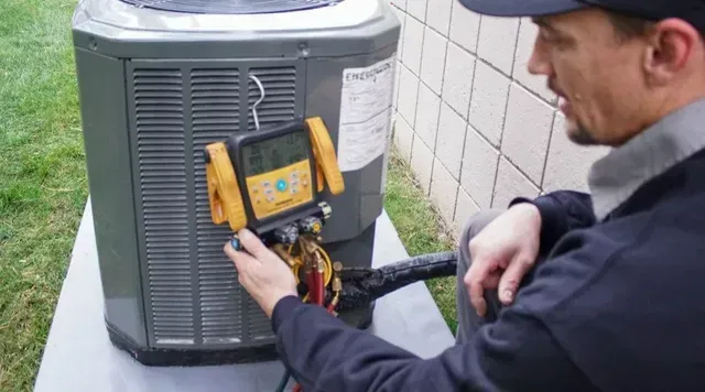 Air conditioning repair technician in safety gear fixing AC unit | Rochester, MI | McQuade HVAC
