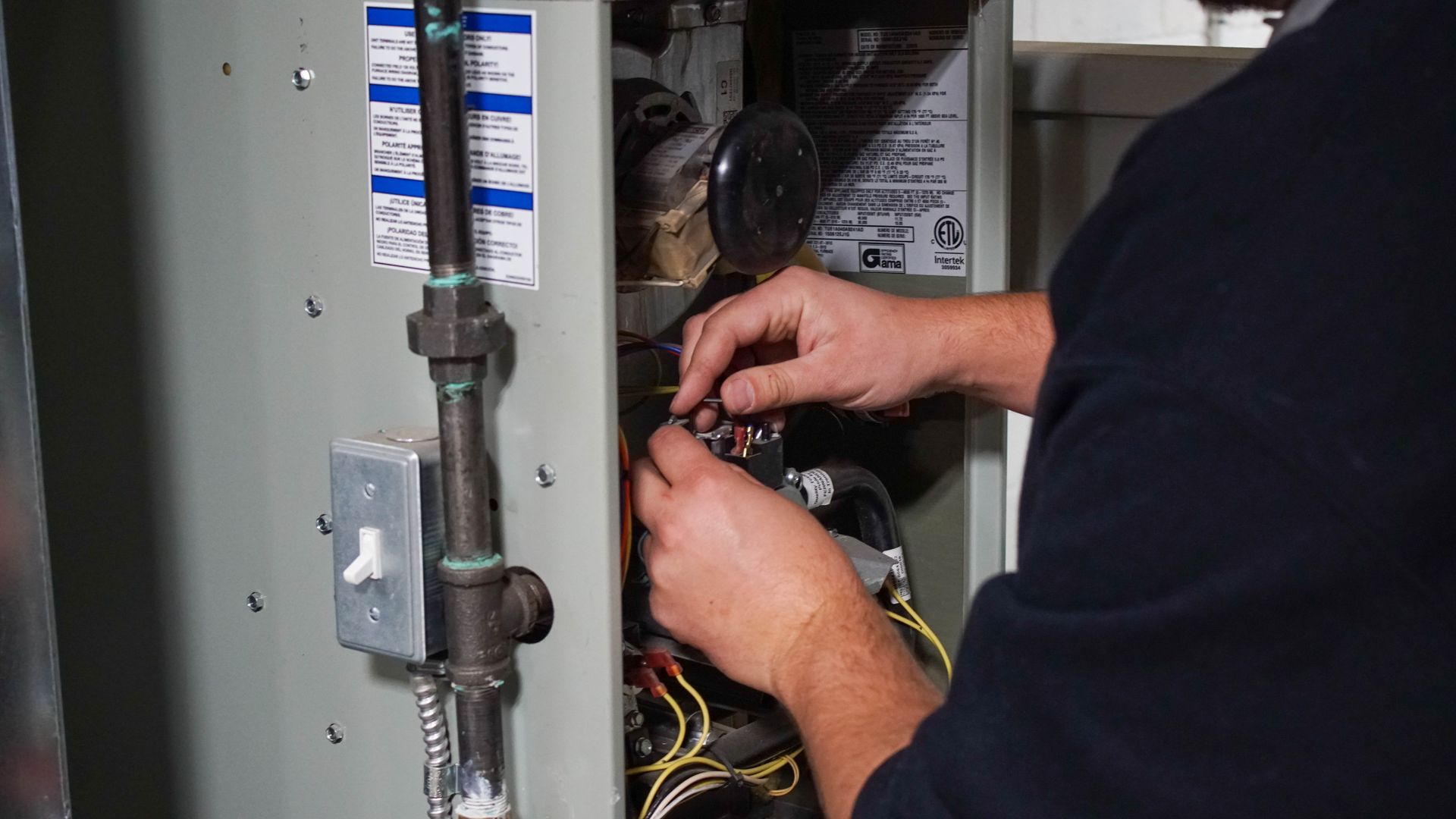 Tech adjusts furnace wiring during repair, ensuring safe HVAC system operation.