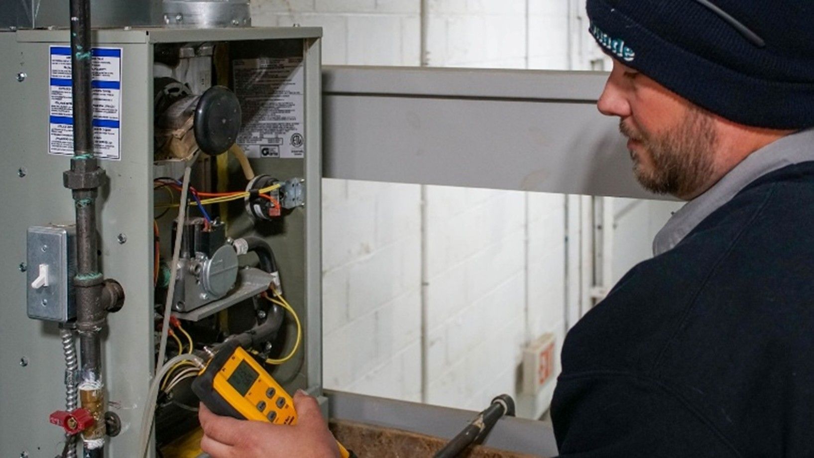 A technician performing maintenance on an indoor boiler system.